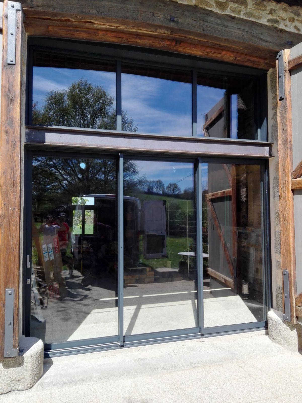 Baie coulissante aluminium gris anthracite dans une grange en pierre