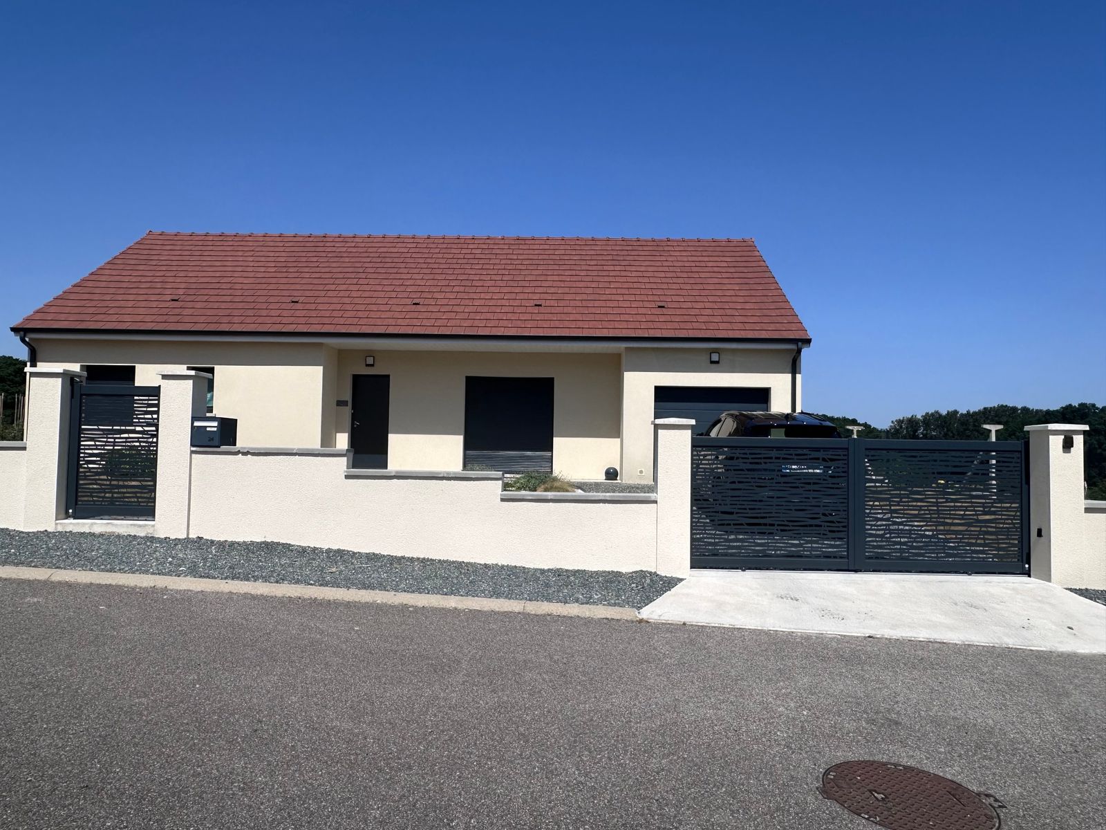 Portail coulissant et portillon aluminium ajourés devant une maison neuve