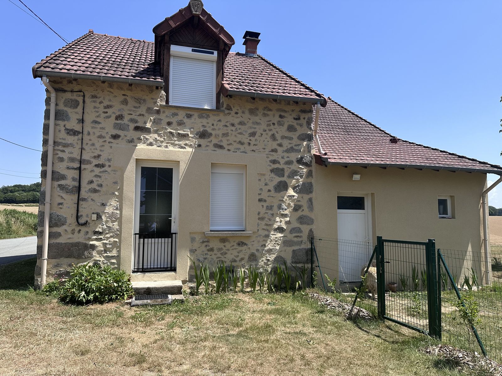 Porte d'entrée et volets roulants blancs sur maison en pierre