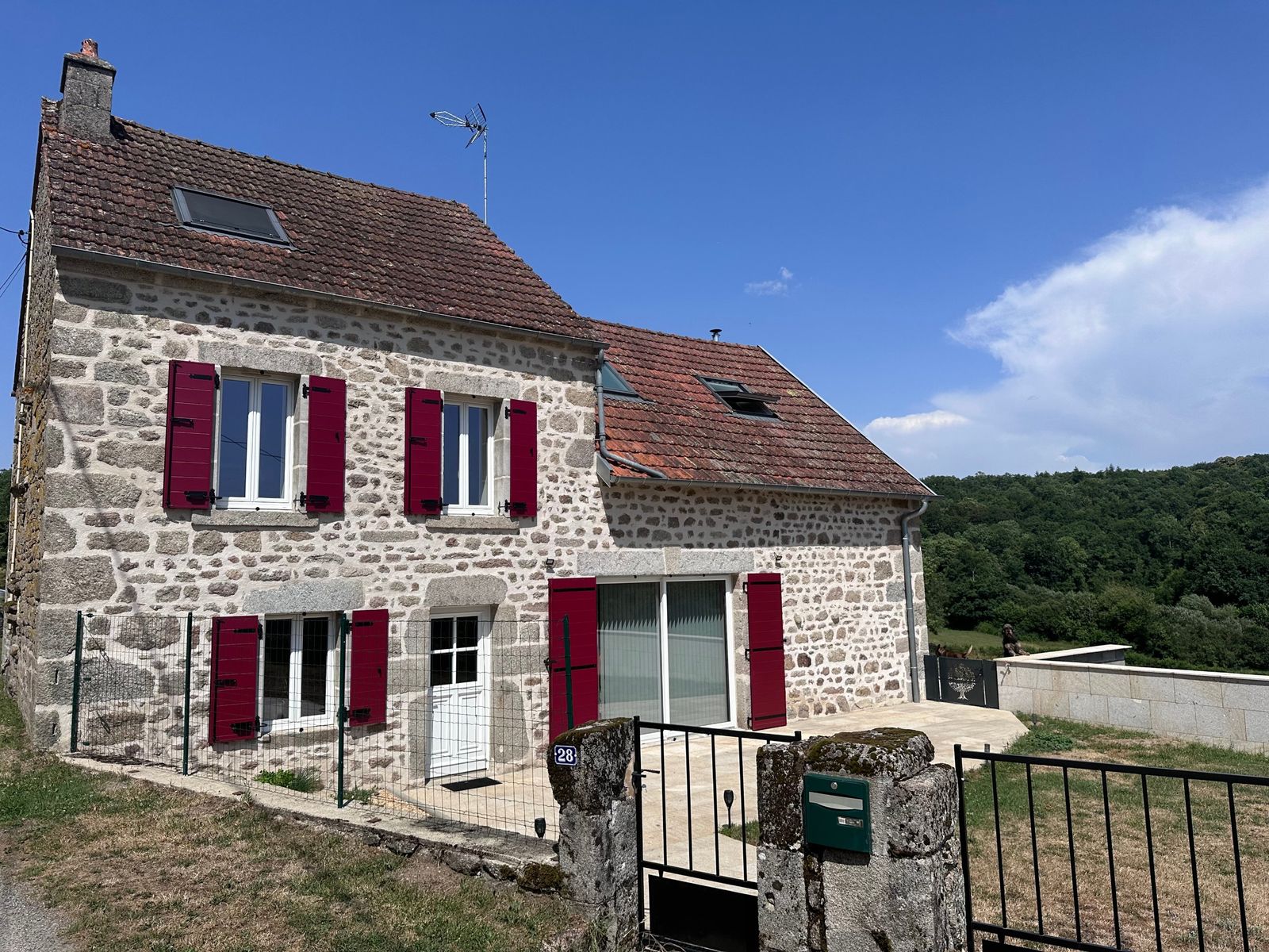 Volets battants bordeaux sur maison en pierre