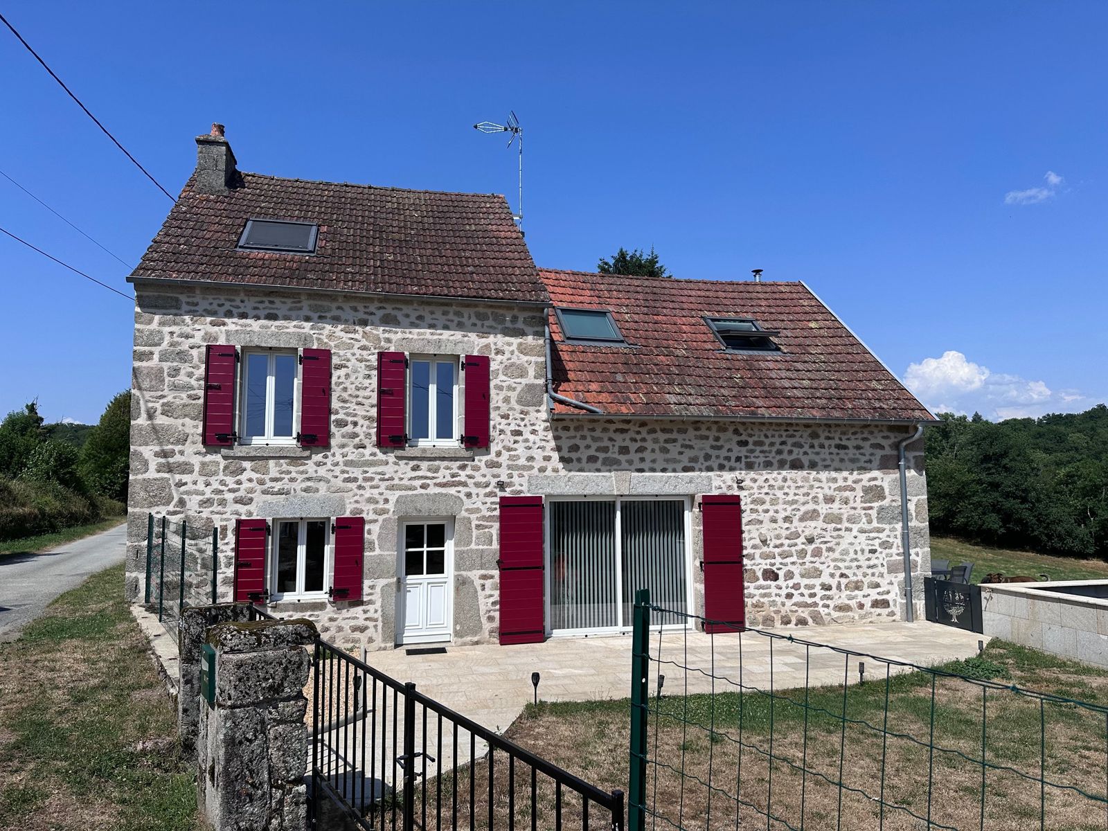 Volets battants bordeaux sur une maison en pierre